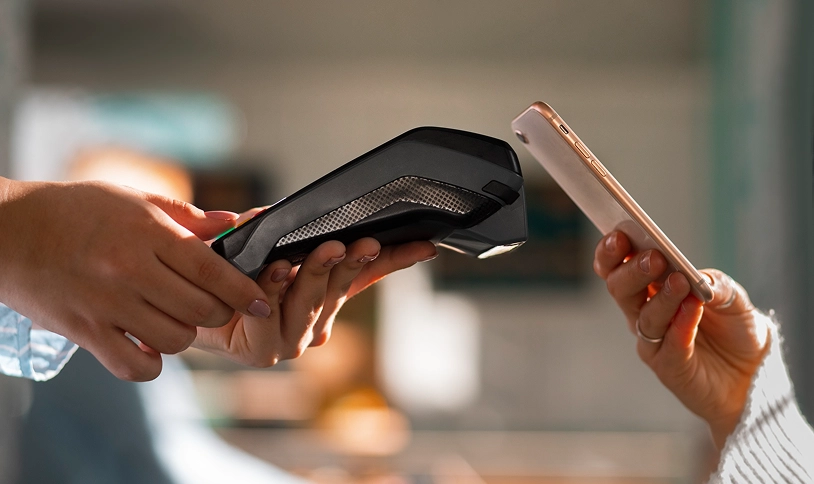 Persona pagando con su teléfono en un terminal de pago.